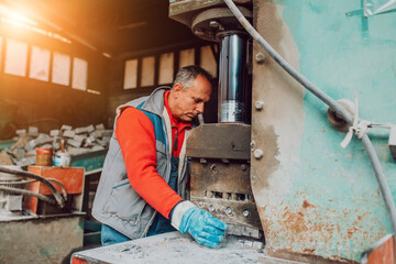 A worker in heavy industry breaks stone blocks using large machines. Granite and stone processing industry.