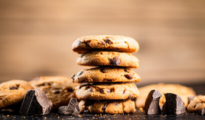 Pile of homemade cookies with pieces of milk chocolate on the table.