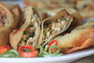 Indonesian snack called mini martabak filled with tofu in a white plate on a wooden table