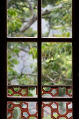 Wooden window revealing the beauty of a tropical setting, through a glass, with a porch