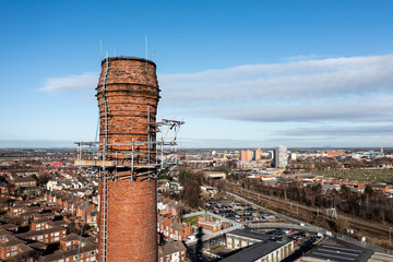 Aerial view of the top of a tall red brick chimney with scaffold