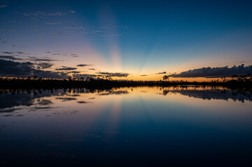 Colorful twilight sun rays over and reflected in Pine Glades Lake in Everglades National Park, Florida..
