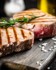 Grilled tuna on a cutting board with a sprig of rosemary. 