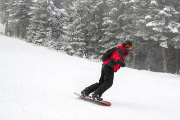 Snowboarder riding down a mountain slope. Winter vacation concept.