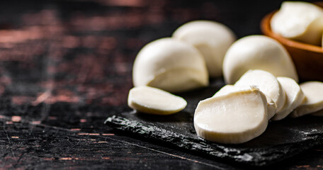 Pieces of mozzarella cheese on a stone board. 