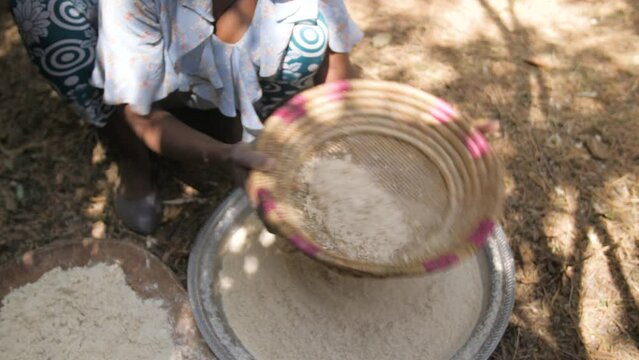 A woman shakes and filters teff flour to make patties, in Ethiopia
