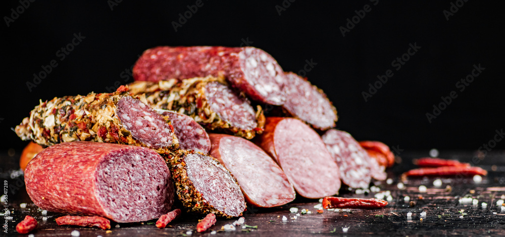 Wall mural a variety of types of salami sausage with dried chili peppers on the table.