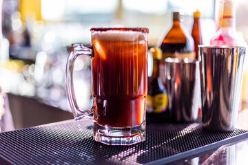Preparación de michelada, cerveza en tarro en restaurante preparada con pepino, camarón, chile chamoy, apio y Clamato	