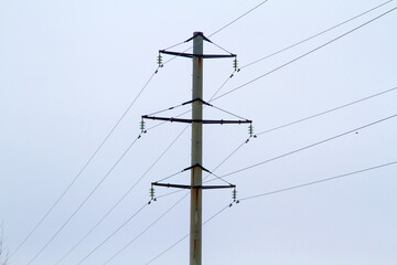 New large mast of an air power line close up, high voltage electricity pylon with thick wires and insulators, blue sky on background. Traditional energy. Electric power concept.