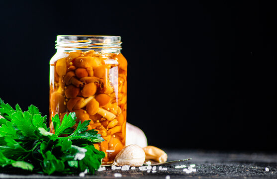 A glass jar with marinated mushrooms on the table.