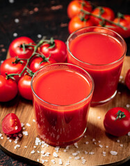 Tomato juice in glasses on a wooden cutting board. 