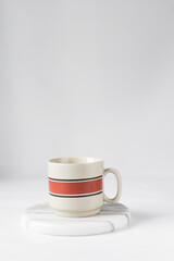 Cream and red ceramic cup on a white marble saucer, Cream and red teacup