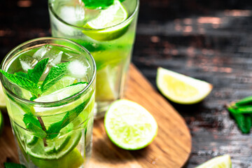 Mojito with pieces of lime on a cutting board.