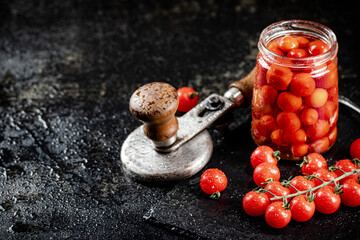 Pickled tomatoes in a jar on a stone board. 