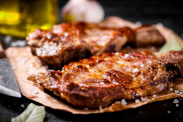 Grilled pork steak on paper on the table. 