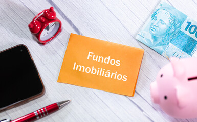 A palavra Fundos Imobiliários escrita em um pedaço de papel que está sobre uma mesa de madeira....