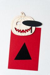 wooden pumpkin ornament with big toothy smile and black paper oval eye patch on red card with up arrow