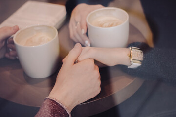 Cute brunette loving couple in cozy warm sweaters on a date at the cafe looking at the phone, using it. cold autumn, winter or spring day, european city. indoors