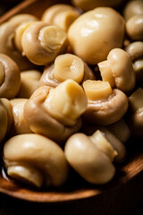 Pickled mushrooms in a wooden plate on the table. 