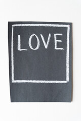 box with the word "love" in white chalk on black paper isolated on white