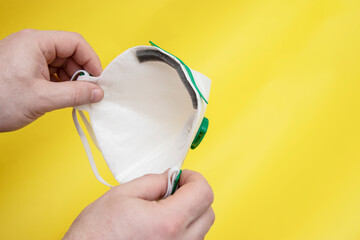 Person hand holds a fpp3 mask on yellow background. Masks needed for emergency coronavirus covid 19