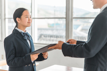 卒業式で先生から卒業証書・賞状・感謝状を受け取る制服の中学生・高校生・小学生の女の子（アジア人）
