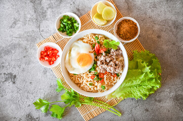 noodles bowl with boiled egg minced pork vegetable spring onion lemon lime lettuce celery and chili on table food , instant noodles cooking tasty eating with bowl noodle soup