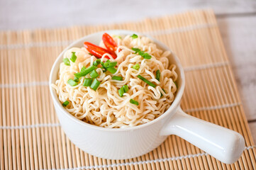 noodles bowl with vegetable spring onion and chili on wooden table, instant noodles cooking tasty eating with bowl