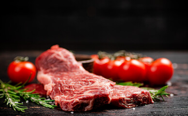 Raw steak with rosemary and spices on the table. 