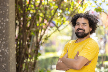 Naklejka na ściany i meble portrait of a Mexican man smiling with curly hair and beard arms crossed copy space