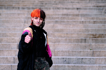 Portrait of a boy with urban appearance with hair painted with the thumb up.