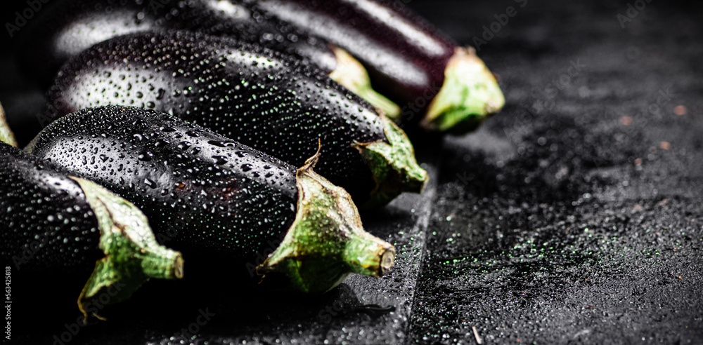 Canvas Prints Fresh ripe eggplant with droplets of water on a stone board. 