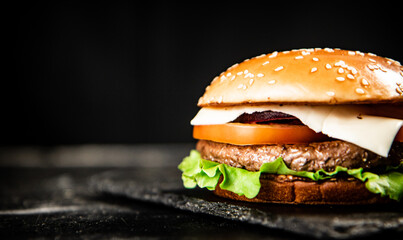 A burger on a stone board on a table. 