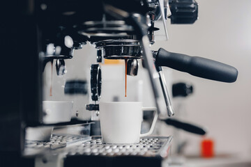 Professional espresso pouring from coffee machine in cafe, cold toning