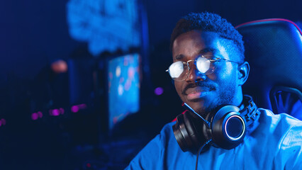 Portrait young American African man professional gamer of online video game with headphones, neon...