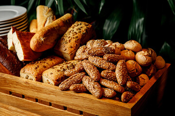 The mix of various fresh baked bread in a wooden basket.