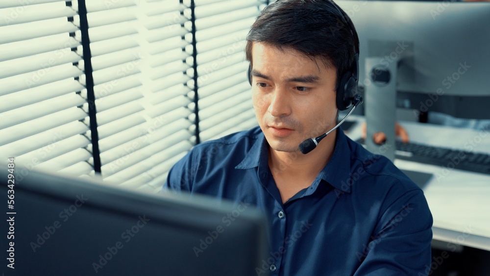 Aufkleber young competent asian male call center agent working at his computer while simultaneously speaking w