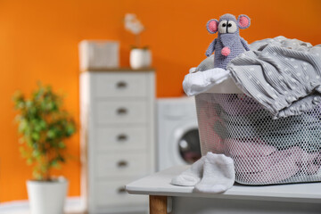 Laundry basket with baby clothes and toy on table in bathroom, closeup. Space for text