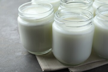 Obraz na płótnie Canvas Tasty yogurt in glass jars on grey table, closeup