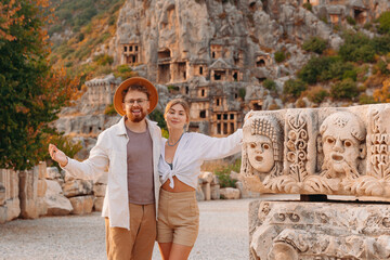 Naklejka premium Happy lover couple tourist archaeologist in hat background old tomb Myra Ancient City in Demre to Antalya, archaeology of Turkey