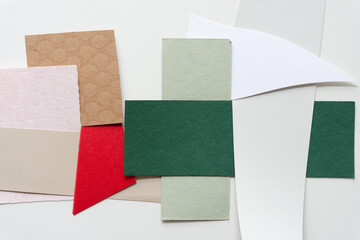 mostly green, red, and pink abstract paper shapes (some geometric) on blank paper