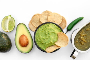 Delicious guacamole made of avocados, nachos and green pepper on white background, top view
