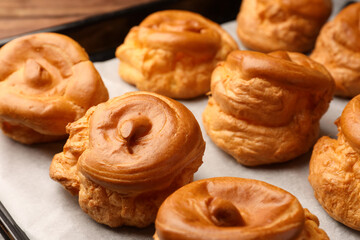 Delicious fresh profiteroles on baking pan, closeup