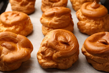 Delicious fresh profiteroles on baking pan, closeup