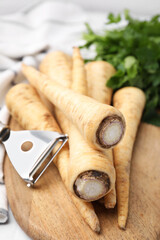 Raw parsley roots and peeler on table, closeup