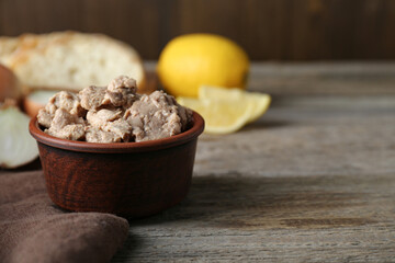 Bowl of tasty cod liver on wooden table, closeup. Space for text