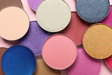 Different beautiful eye shadows on pink background, flat lay