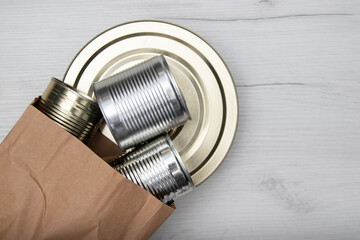 Various closed tin cans with food preserves on a light background. Canned food concept. Food donations. Copy space