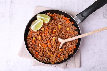 Fried minced meat, carrot, corn and lime in pan on white textured table, top view
