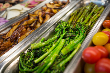 Close-up of green and fresh charred broccolini, in a silver serving container, at a salad bar